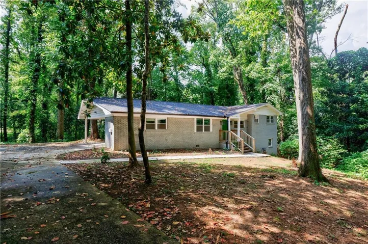 Single story home with basement, brick siding, driveway, a carport, and a porch