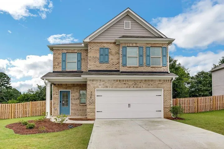 View of front facade featuring a garage and a front lawn