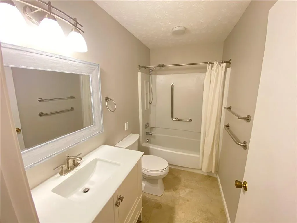 Full bathroom featuring tile patterned flooring, a textured ceiling, toilet, vanity, and shower / tub combo with curtain