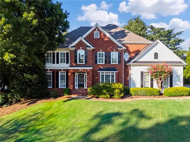 Two-story brick facade with white siding accents and a gabled roof