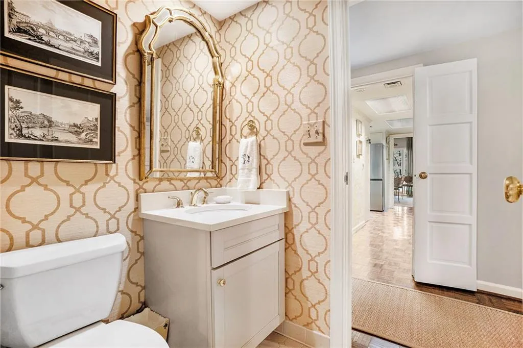 Half bathroom with wallpapered walls and vanity Half bathroom with wallpapered walls and vanity