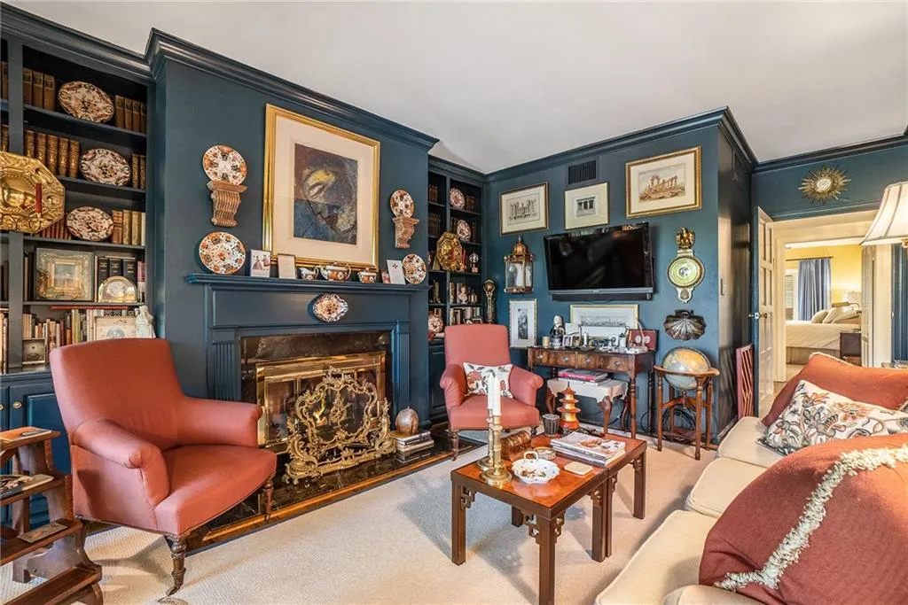 Carpeted living area with crown molding, a fireplace with raised hearth, and built in shelves Carpeted living area with crown molding, a fireplace with raised hearth, and built in shelves