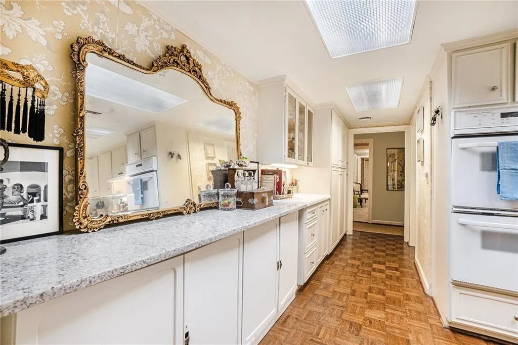 Kitchen featuring white double oven, white cabinetry, and glass insert cabinets Kitchen featuring white double oven, white cabinetry, and glass insert cabinets
