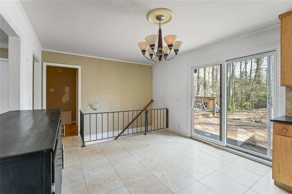 Tiled dining area inviting chandelier and ornamental molding. Stairs leading down to the partial finished basement.