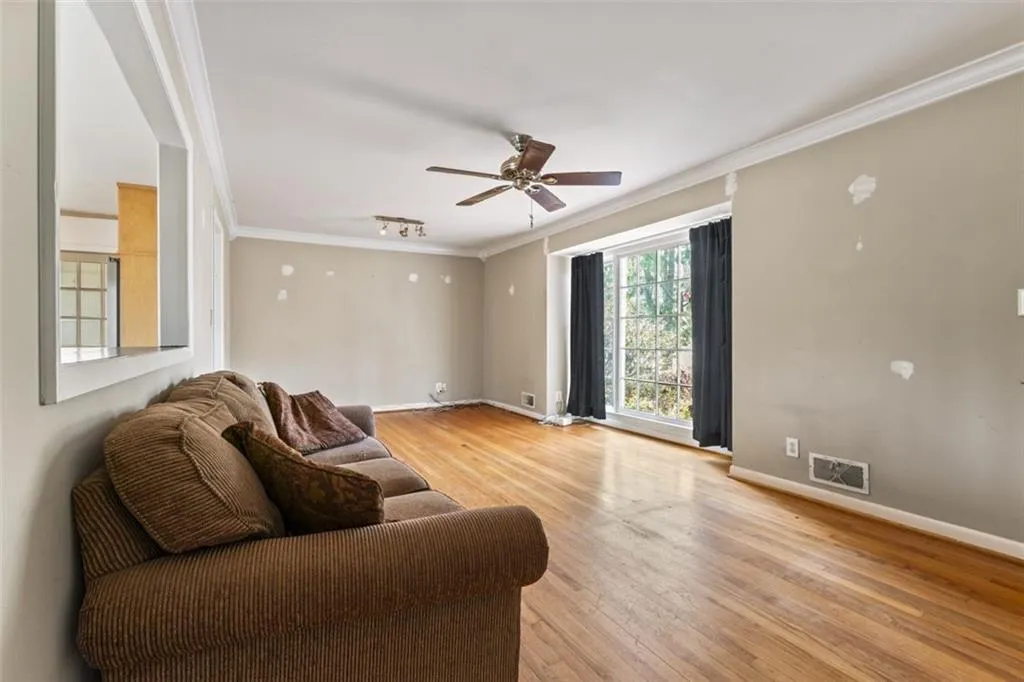 Living room featuring crown molding, light hardwood flooring, and ceiling fan.