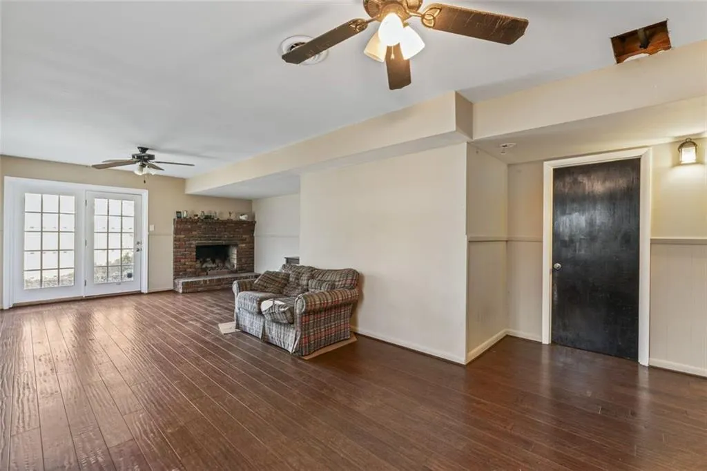 Living room featuring a fireplace, dark wood-type flooring, and ceiling fan