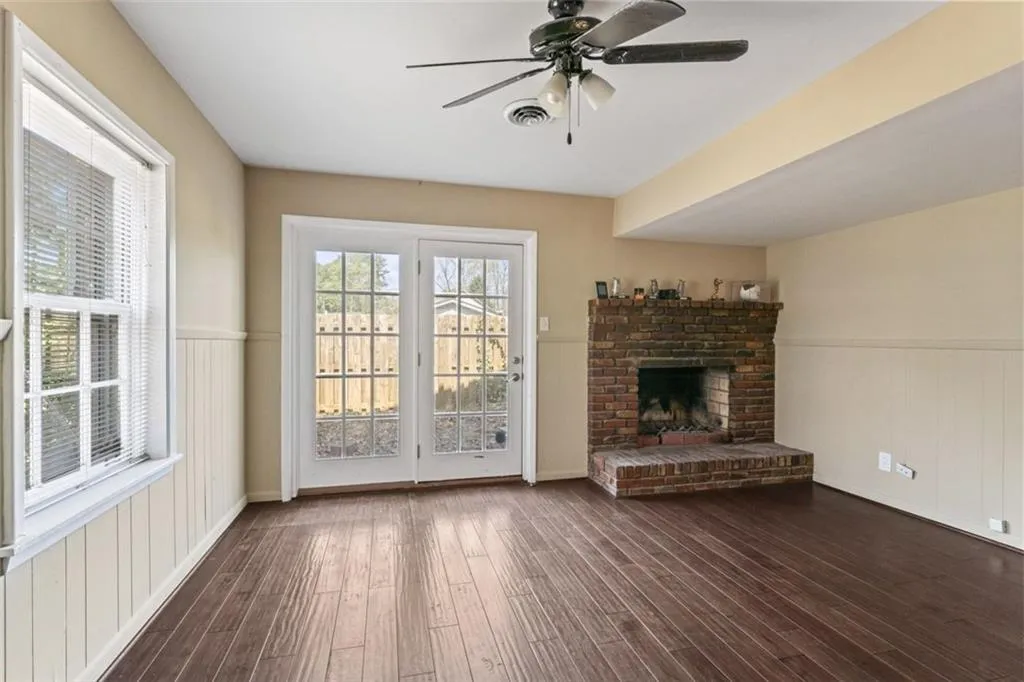 Basement sitting room/flex space featuring a brick fireplace, a wealth of natural light, dark wood-type flooring, and ceiling fan