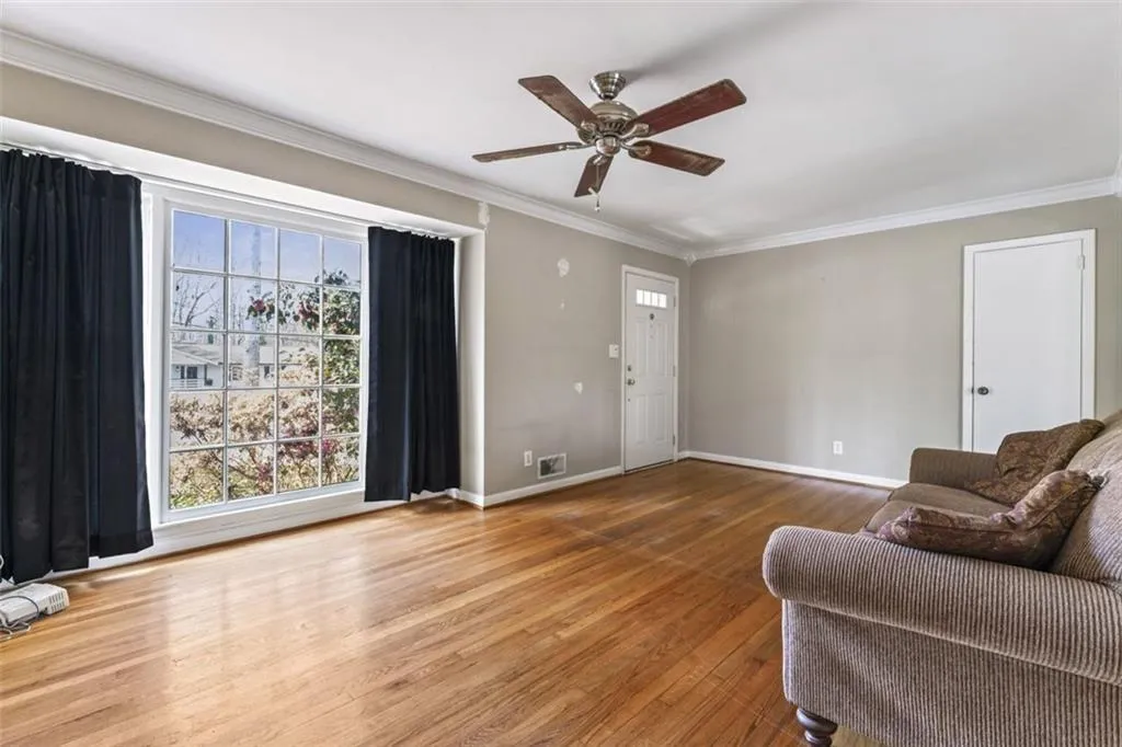 Living room featuring crown molding, hardwood floors, and ceiling fan