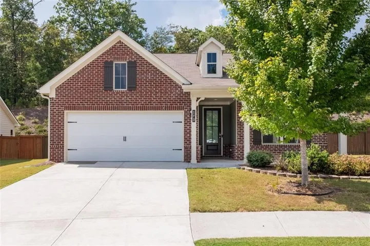 Brick exterior with white trim, a covered entry, and an attached two-car garage