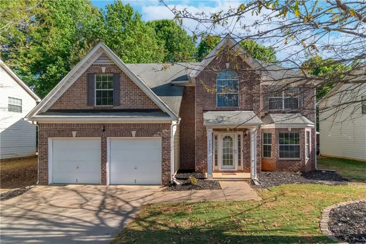 Brick exterior with a prominent arched window, two-car garage, covered porch entry, and a bay window