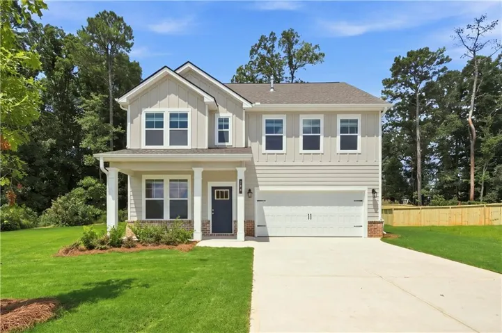 Two-story exterior with light-toned siding, a covered entry, an attached garage, a driveway, and a fenced perimeter