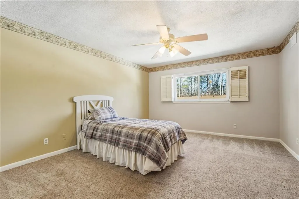 Bedroom featuring carpet floors, ceiling fan, and a textured ceiling