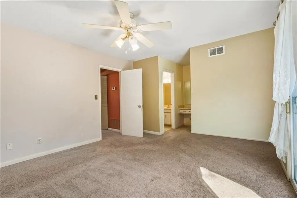 Unfurnished bedroom with light carpet, connected bathroom, and ceiling fan