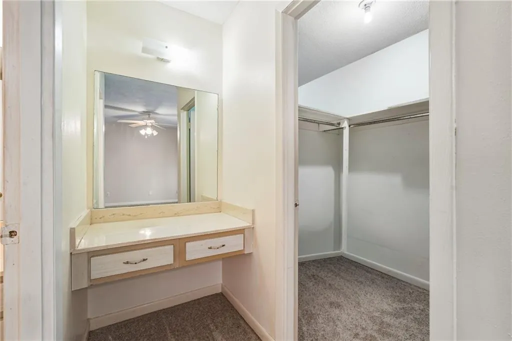 Bathroom with a spacious closet, dark carpet, and vanity
