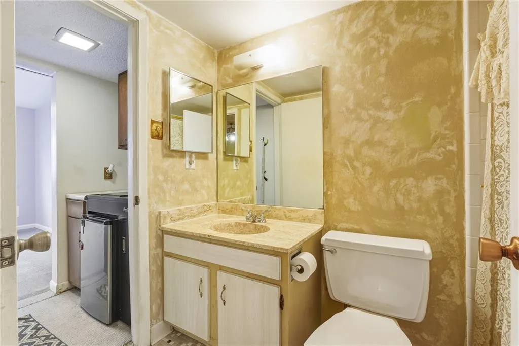 Full bathroom featuring vanity, a shower with curtain, independent washer and dryer, and a textured ceiling