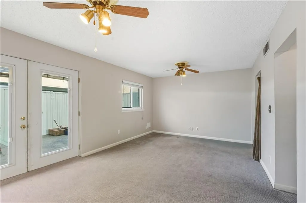 Empty room featuring french doors, a ceiling fan, carpet flooring, and a textured ceiling