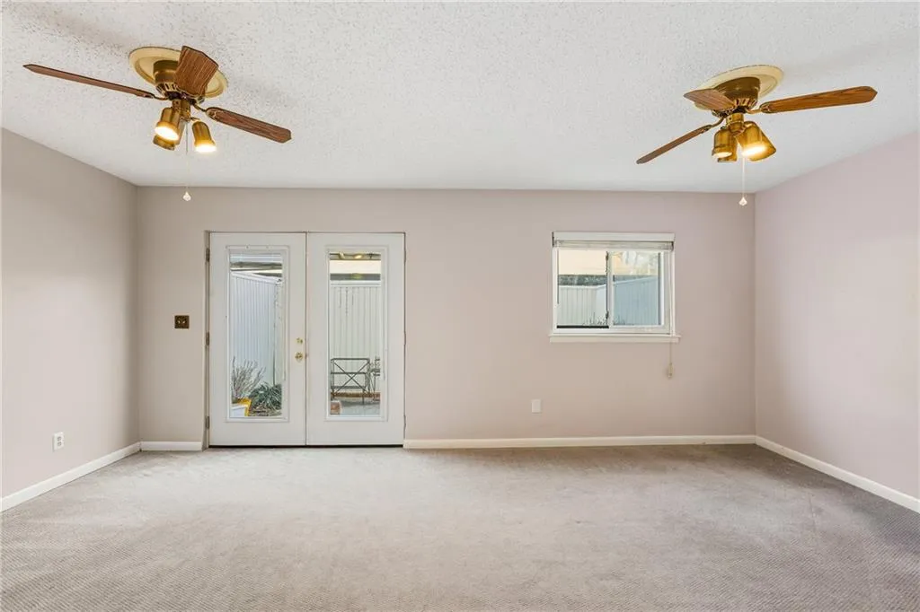 Carpeted spare room featuring a ceiling fan, french doors, and a textured ceiling