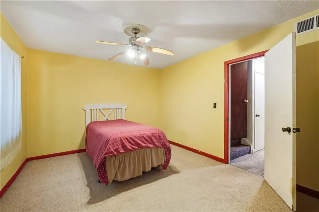 Basement level Bedroom with light colored carpet and ceiling fan