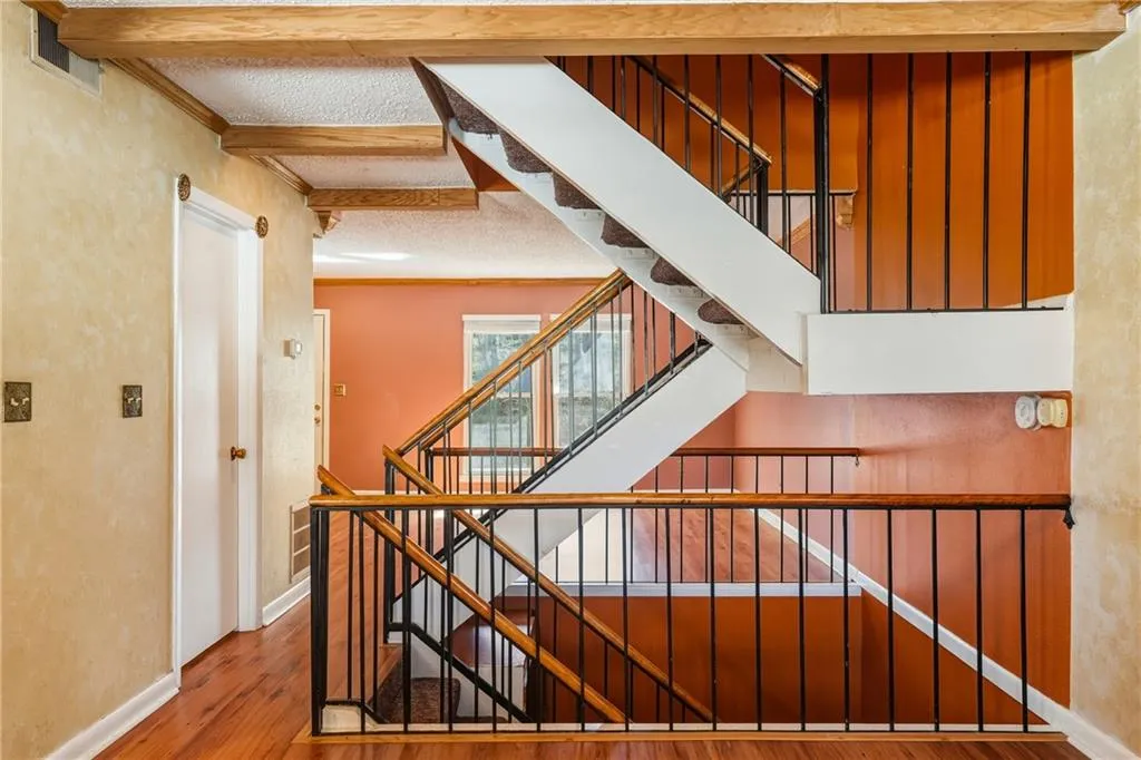Stairway with wood finished floors, a textured ceiling, ornamental molding, and a textured wall