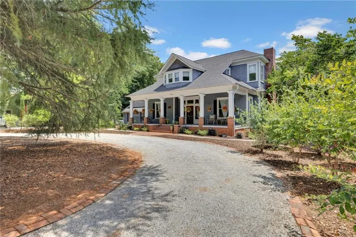 Traditional-style residence featuring a prominent covered porch with white columns and a brick foundation