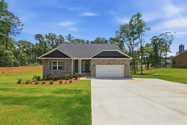 Brick exterior with a dark shingle roof, attached garage, and concrete driveway
