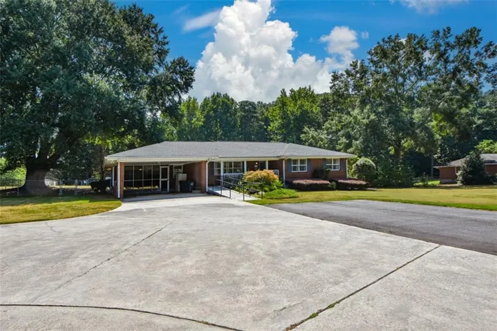 Brick facade home with covered carport, screened porch, and concrete driveway