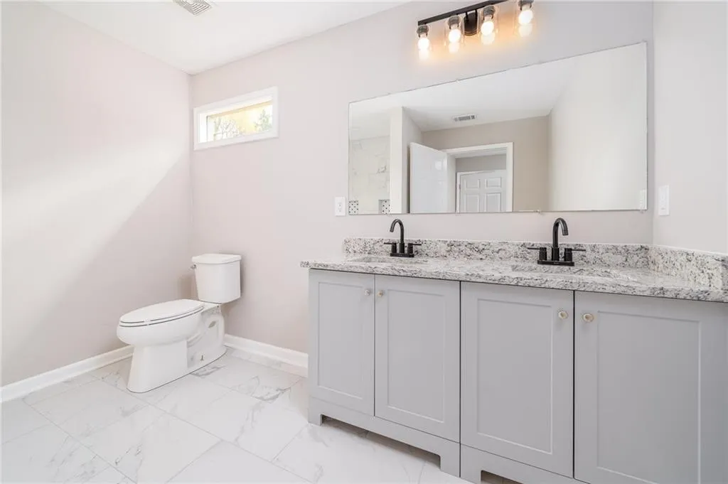 Bathroom with double vanity and light marble finish floors