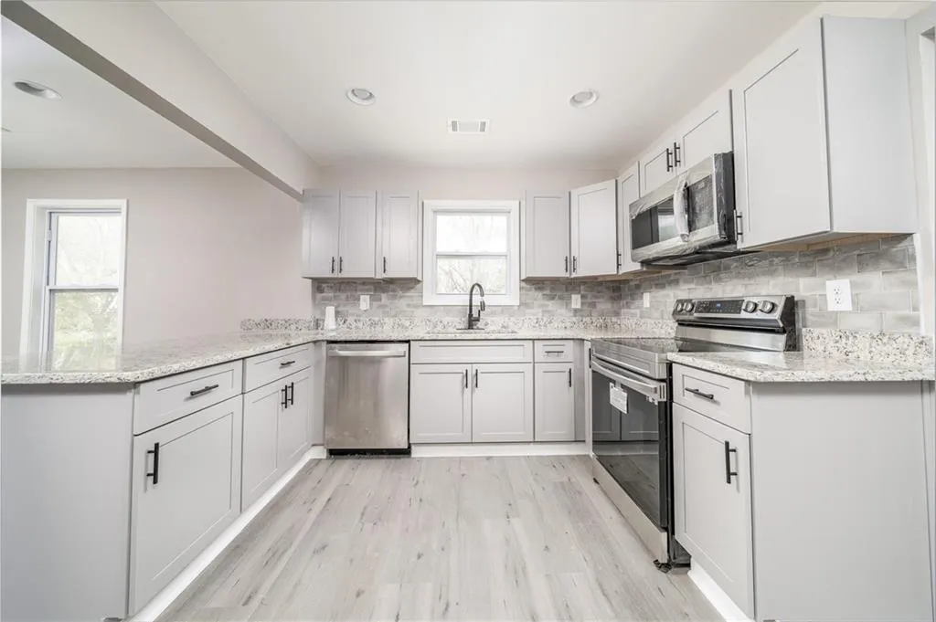 Kitchen featuring appliances with stainless steel finishes, light stone countertops, tasteful backsplash, recessed lighting, and light wood-type flooring
