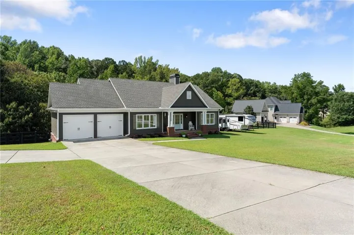 Exterior featuring dark siding, white trim, a covered front porch, a two-car garage, and a concrete driveway