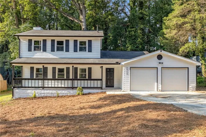Two-story residence with a covered front porch featuring a black railing, a two-car garage with white doors, and a concrete driveway