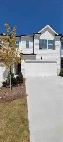 White horizontal siding exterior with dark shutters, attached garage, concrete driveway, and front landscaping
