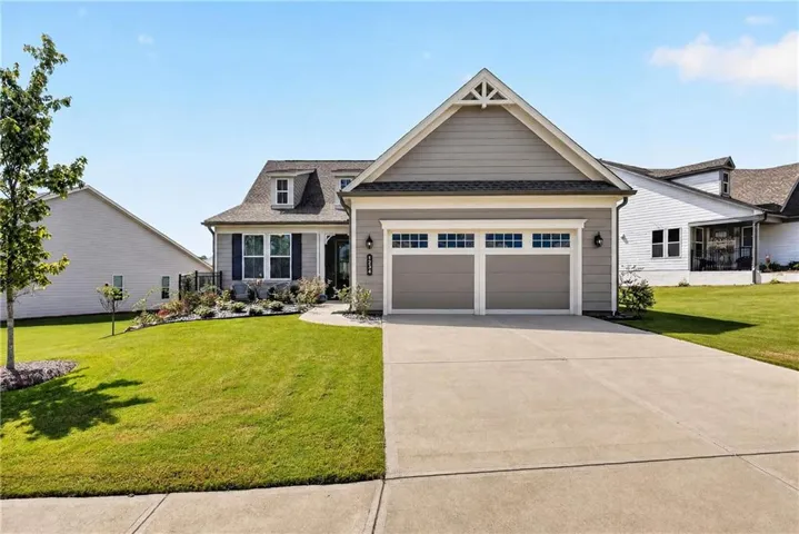 Siding exterior with dormer windows, a two-car garage, concrete driveway, and established landscaping