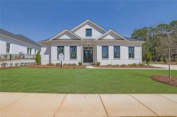 View of front of house featuring brick siding, fence, and a front lawn