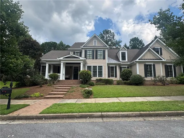 Siding exterior with black shutters, brick walkway, and covered front porch