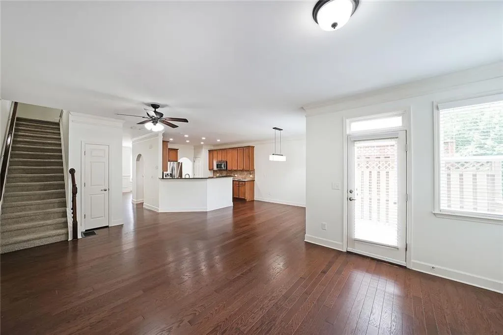Unfurnished living room with ceiling fan, crown molding, dark wood-style floors, stairs, and recessed lighting