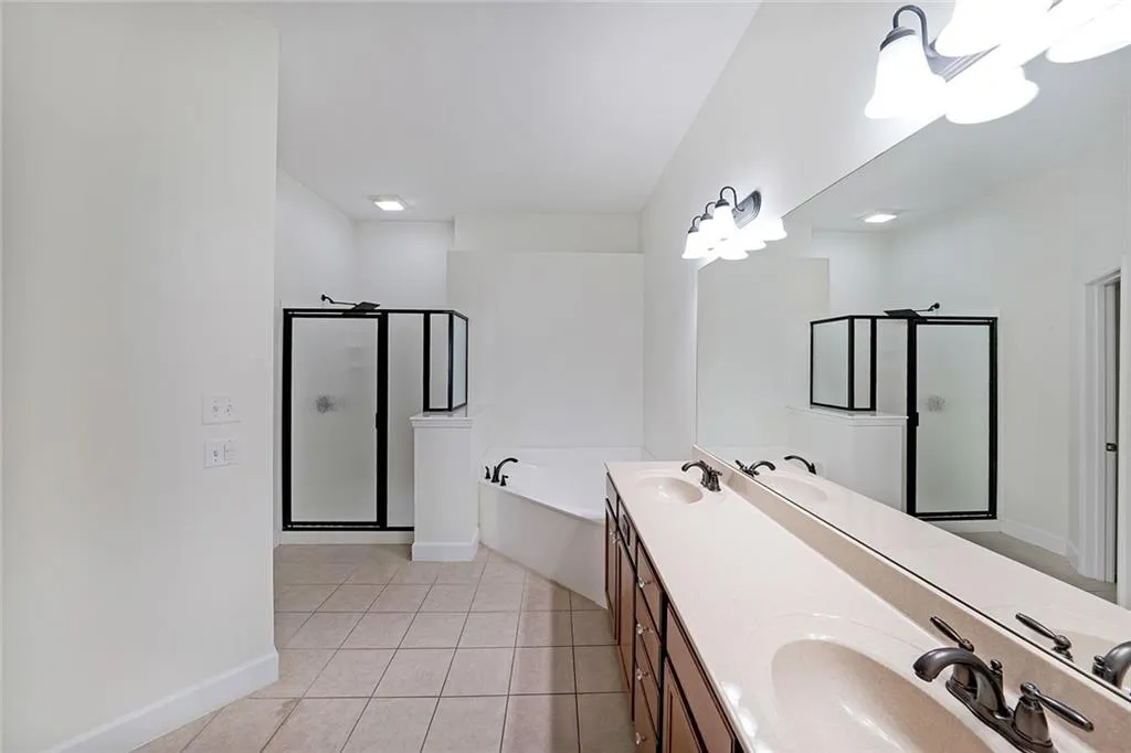 Full bathroom featuring a stall shower, a bath, double vanity, and tile patterned floors