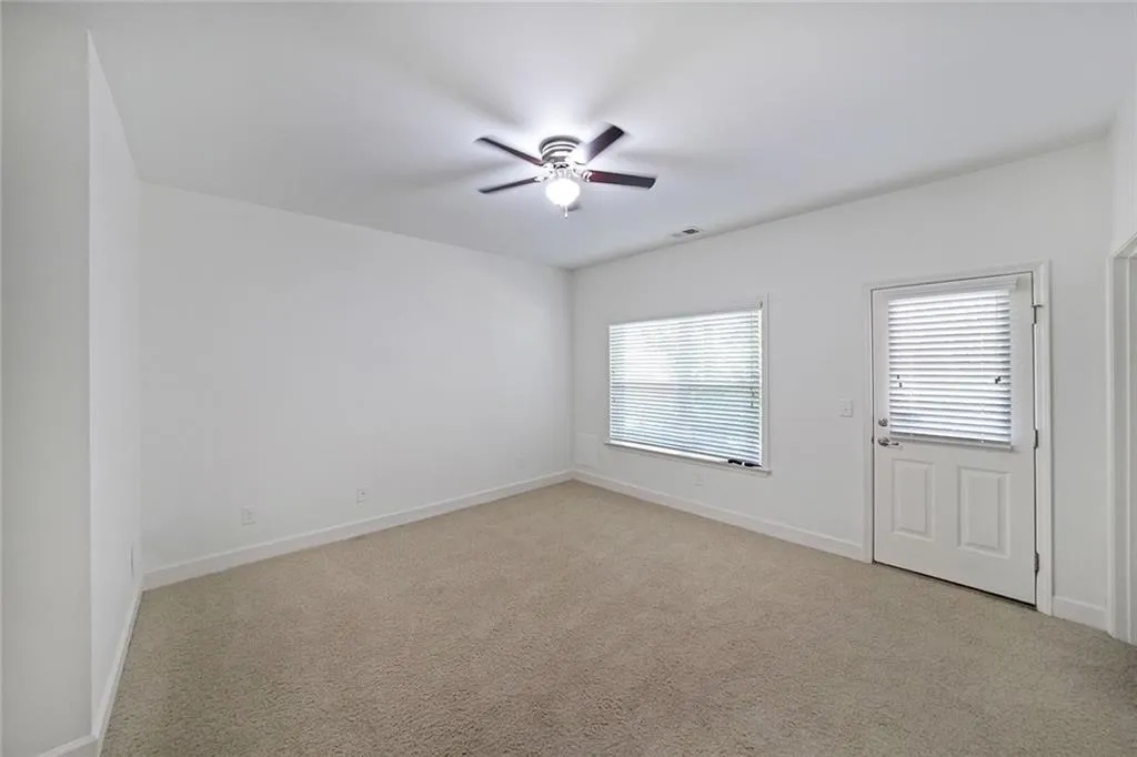 Empty room with a ceiling fan and light carpet