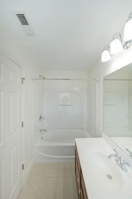 Bathroom featuring  shower combination, vanity, and tile patterned flooring