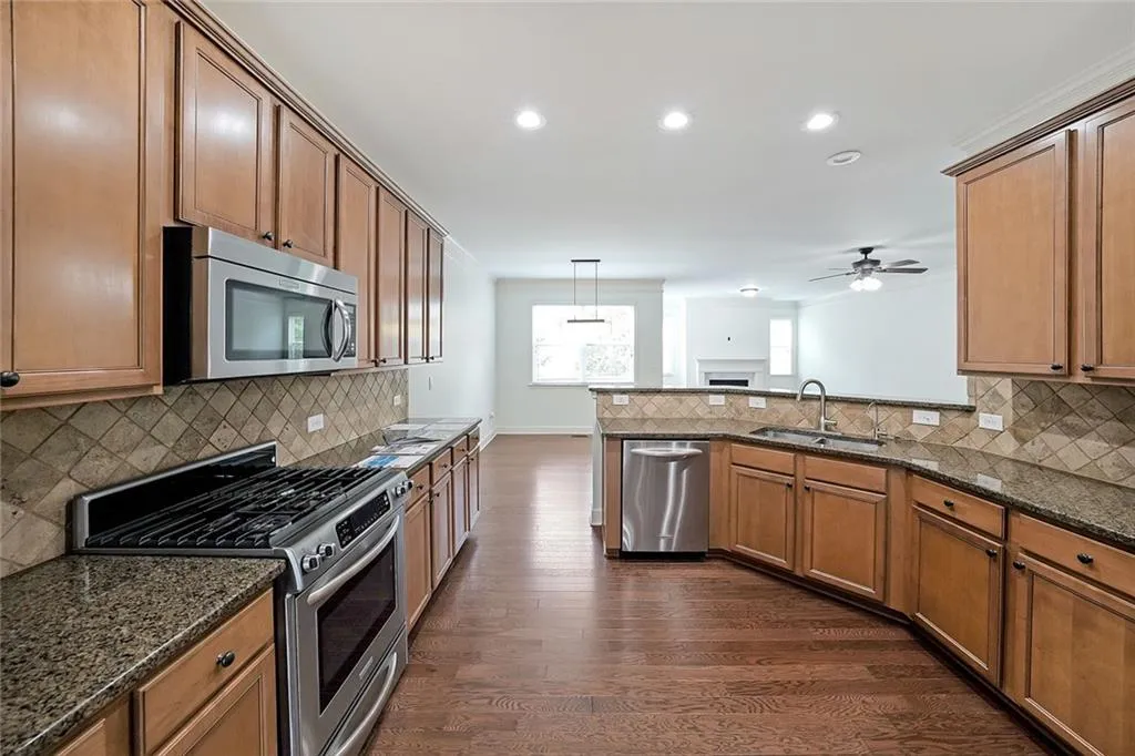 Kitchen with stainless steel appliances, dark wood-type flooring, recessed lighting, ceiling fan, and backsplash