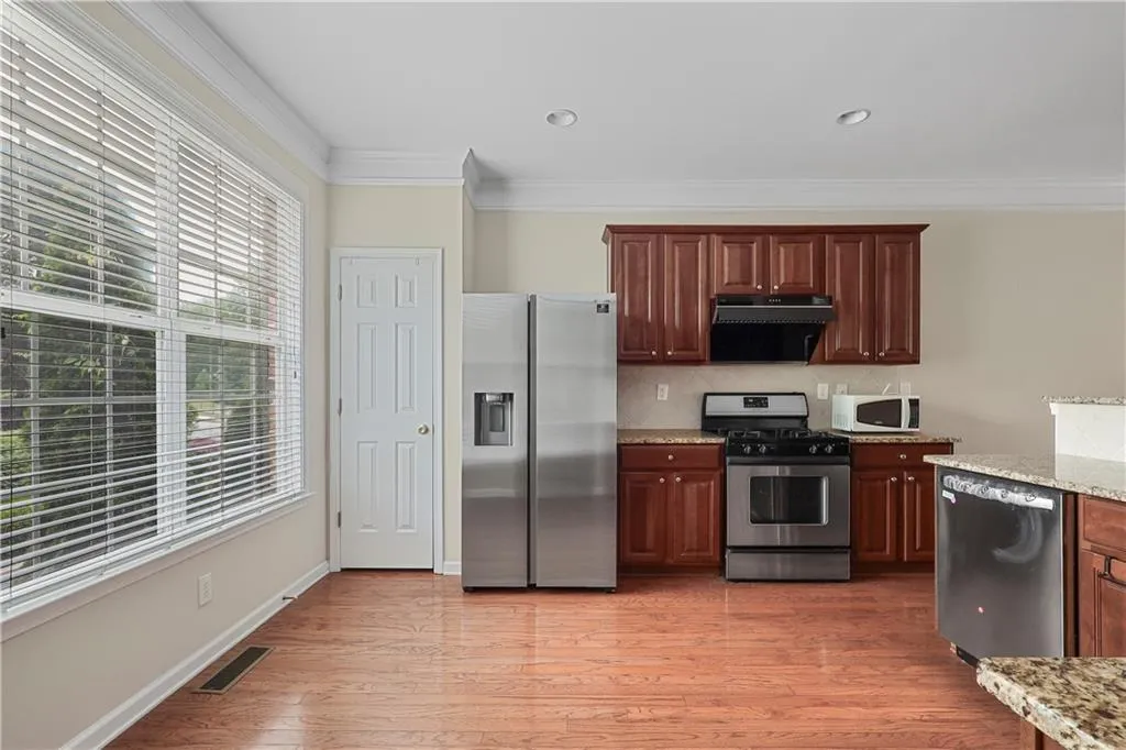 Kitchen with visible vents, ornamental molding, light stone countertops, and stainless steel appliances