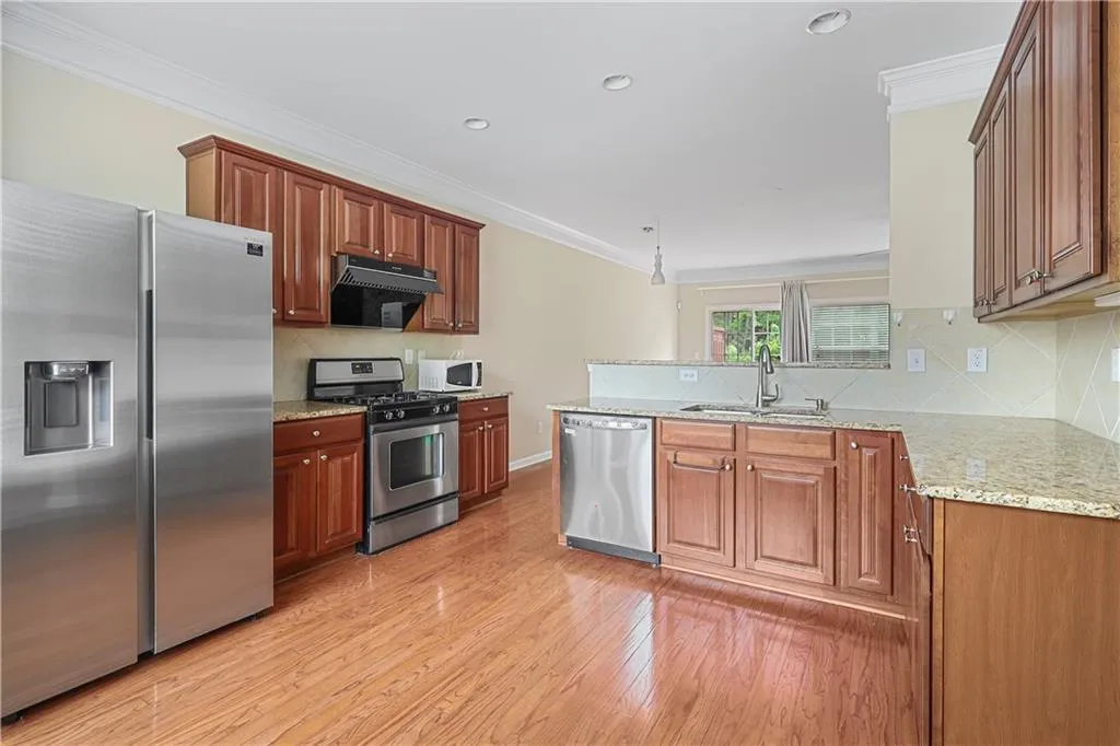 Kitchen featuring a sink, light wood-style flooring, appliances with stainless steel finishes, and ornamental molding