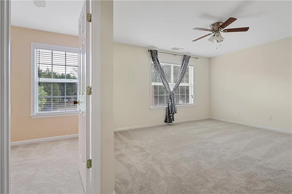 Empty room with baseboards, visible vents, a ceiling fan, and light colored carpet