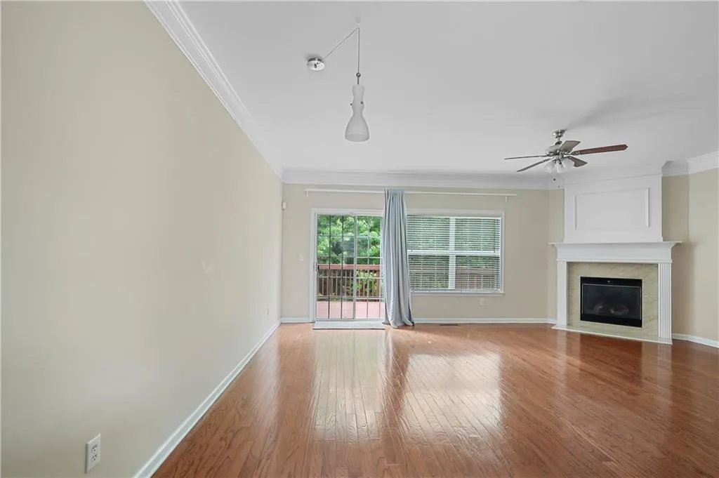 Unfurnished living room with crown molding, baseboards, ceiling fan, and light wood-type flooring