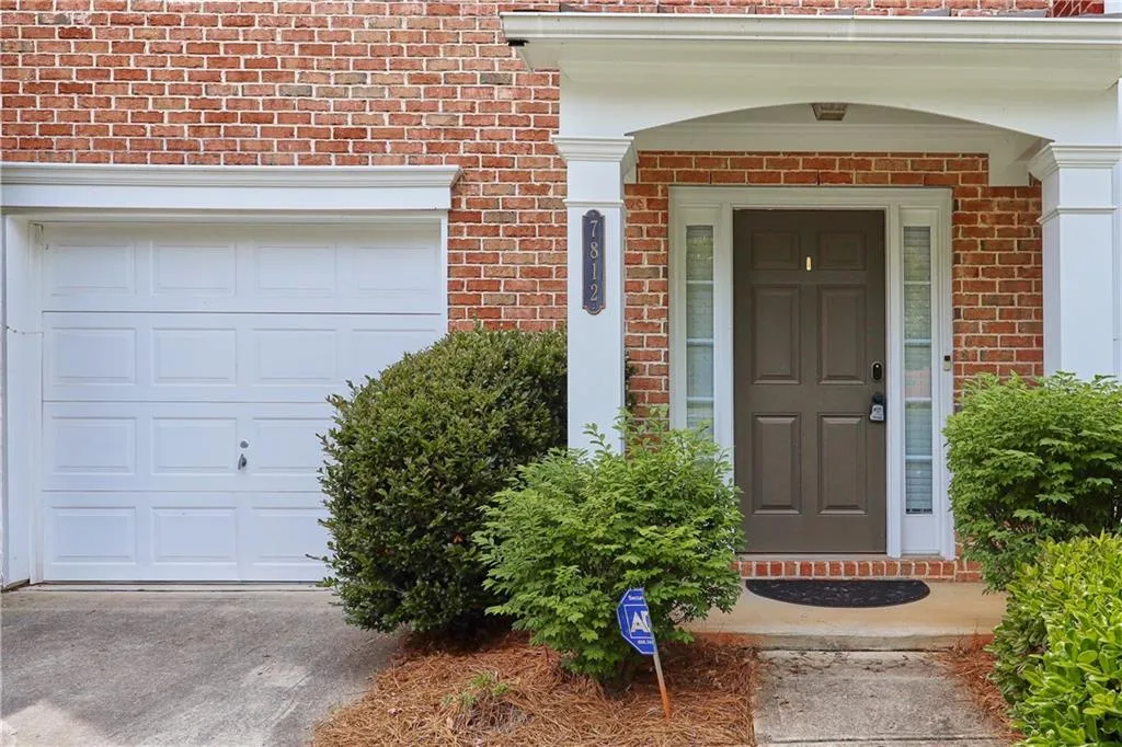 View of exterior entry with brick siding and a garage
