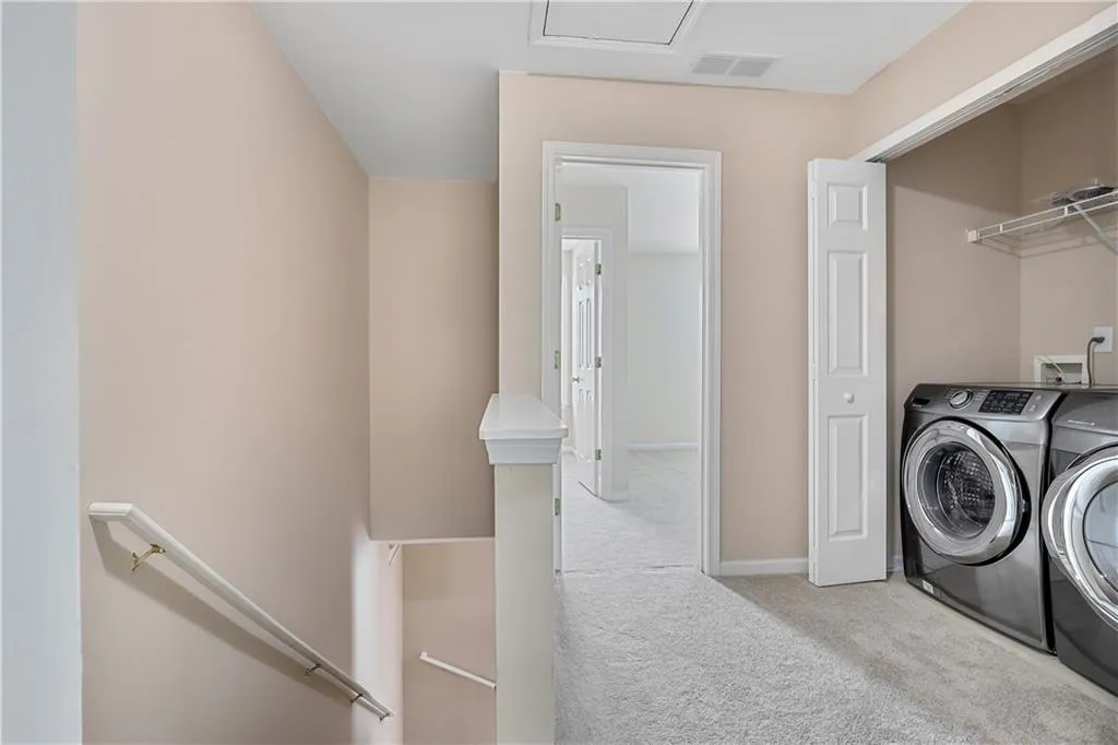 Clothes washing area with washer and dryer, laundry area, carpet, baseboards, and visible vents