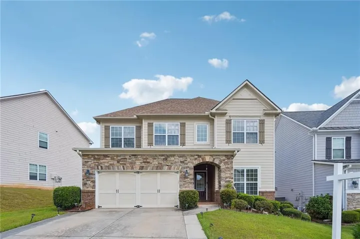 Traditional two-story residence featuring a stone-clad garage and entry archway