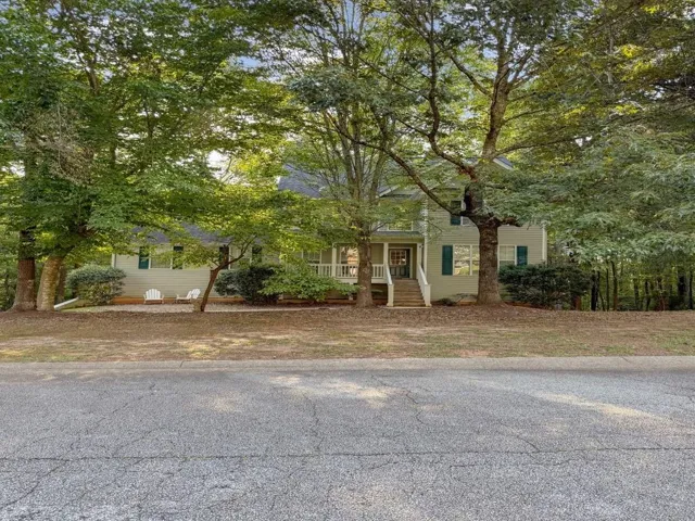Two-story exterior with a covered front porch featuring white railing, dark green shutters, and a prominent front entrance with a windowed door