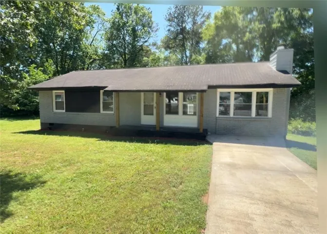 Ranch-style residence featuring a gray brick exterior, a covered porch with wooden posts, and a concrete driveway