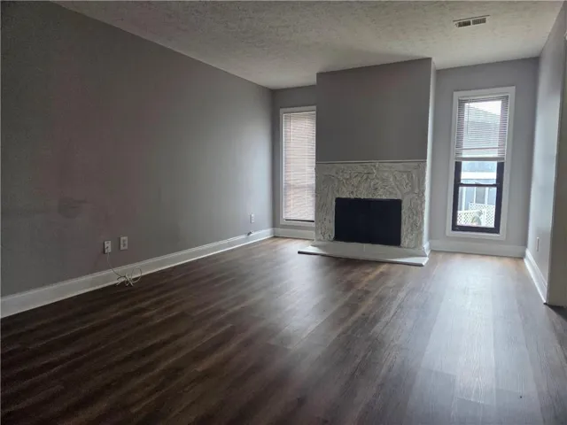 Living space featuring wood-finish flooring and a decorative stone-surround fireplace