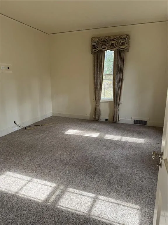 Empty room featuring carpet and baseboards